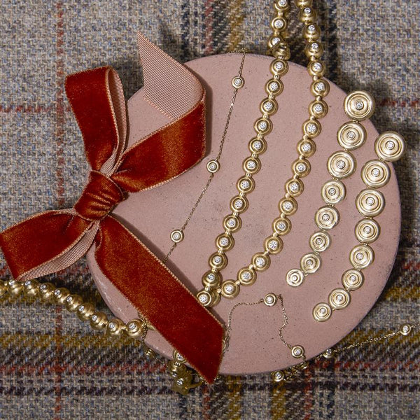 A pink box decorated with pearls and a red ribbon, representing heartfelt Christmas jewelry gift ideas for women.