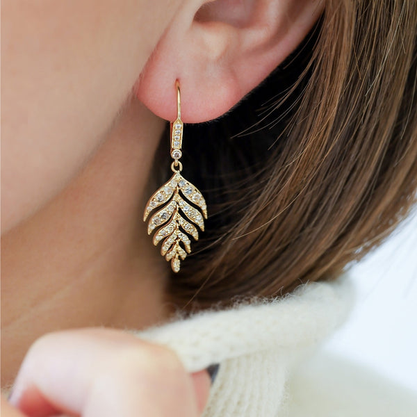  A woman showcases a stylish gold leaf earring, embodying contemporary fashion trends.