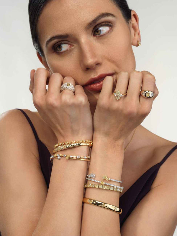 A woman showcases a gold bracelet and ring, highlighting their significance in modern fashion and personal style.